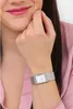 A close-up shot of a woman's wrist wearing a silver watch with a white face. Voir les images du produit