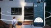 A person walks past a house with a smartphone displaying a security camera app in the foreground. Anteprima dell’immagine prodotto