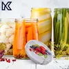 A collection of jars filled with preserved vegetables and fruits, with a decorative lid in the foreground. Voir les images du produit