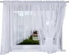 A white lace curtain is shown hanging in a window. Náhled obrázku produktu