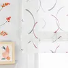 A close-up view of a white Roman blind with a modern abstract pattern of curved lines in gray and pink. To the left, a white wall with three decorative orange floral sprigs and a framed picture of vases and fruit. Produktbild-Vorschau