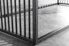 A close-up view of the corner of a black metal frame, possibly a table or a cage, resting on a concrete floor. Produktbild-Vorschau
