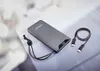 A gray power bank with a charging cable on a light gray surface. Voir les images du produit