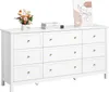 A white dresser with nine drawers, decorated with a vase of flowers and books on top. Náhled obrázku produktu