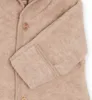 A close-up view of a beige baby overall, showing the fabric texture, a wooden button, and the sleeve cuff. Produktbild-Vorschau