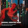 A person is sitting in front of a red Marshall speaker, with a city skyline in the background. Produktbild-Vorschau