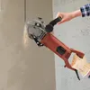 A person is using a wall chaser to cut a groove into a concrete wall, creating dust and sparks. Náhled obrázku produktu