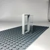 A Lego door frame with a transparent door is placed on a Lego baseplate. Podgląd zdjęcia produktu