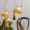 Several glass baubles filled with LED lights hang against a white brick wall. Produktbild-Vorschau