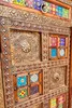 A close-up view of an ornate wooden sideboard with decorative metalwork and colorful tiled inlays. Produktbild-Vorschau