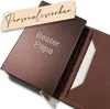 A close-up shot of a brown leather wallet with a metallic brown cardholder inside, featuring engraved text. Produktbild-Vorschau