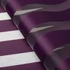 A close-up, angled view of a dark purple roller blind with white and gray striped patterns, folded over itself. Produktbild-Vorschau