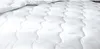 A close-up view of a white quilted comforter or duvet. Produktbild-Vorschau
