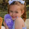 A young girl is holding a purple plush hedgehog toy outdoors. Náhled obrázku produktu