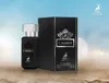 A perfume bottle and its box are displayed on a sandy surface with a blurred sky background. Produktbild-Vorschau