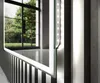 Close-up of a modern mirror with integrated LED lighting, reflecting a room with large windows and greenery. Produktbild-Vorschau