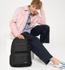 A young man is sitting and posing with a black Eastpak backpack. Produktbild-Vorschau