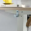 A close-up view of a desk with a book and a yellow mug on top, and a metal hook attached to the underside of the desk. Produktbild-Vorschau