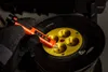 A hand wearing a black glove is holding an orange voltage tester near a black extension cord reel with yellow outlets. Podgląd zdjęcia produktu