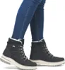 A person wearing blue jeans and black winter boots. Produktbild-Vorschau