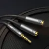 A close-up shot of a Ugreen audio splitter cable with a 3.5mm jack and two female connectors, one for microphone and one for headphones, resting on a textured black surface. Podgląd zdjęcia produktu