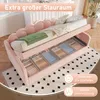 A pink upholstered daybed with storage drawers open, revealing organized items. The bed has a scalloped headboard and is shown in a room setting with a rug. Produktbild-Vorschau