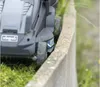 Close-up of a lawnmower next to a concrete border. Náhled obrázku produktu