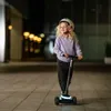 A young girl rides a scooter at night. Produktbild-Vorschau