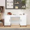 A white desk with cabinets on either side is shown in a well-lit room. There is a pegboard on the wall behind the desk with some decorative items and pictures. A tree with green leaves is also visible on the right side of the image. The desk has a clean an