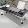 A black folding lap desk is placed on a bed, holding a laptop, a cup of coffee, and a smartphone. Anteprima dell’immagine prodotto