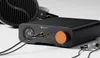 A close-up shot of a black Fosi Audio ZH3 DAC and headphone amplifier with an orange volume knob, connected to headphones and earphones, set against a white background. Produktbild-Vorschau