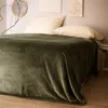 A bed with a green blanket and pillows, with artwork on the wall. Produktbild-Vorschau