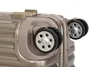 A close-up view of the wheels and corner of a gold suitcase. Podgląd zdjęcia produktu