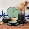 Das Geschirrset steht auf dem Tisch, umgeben von Geschenkboxen mit blauen Bändern, und Blumen. Produktbild-Vorschau