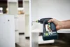 A person is using a cordless drill to assemble white furniture in a workshop. Produktbild-Vorschau