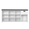 A white shoe cabinet with a gray cushion on top, featuring multiple open shelves and one drawer. Produktbild-Vorschau