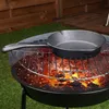 A cast iron pan is placed on a grill over hot coals. Produktbild-Vorschau
