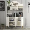 A cream-colored cabinet with gold accents, designed as a coffee bar, is shown in a room setting. It features shelves displaying various kitchen items like mugs, a coffee maker, and an air fryer. Produktbild-Vorschau