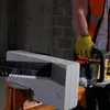 A person wearing a safety vest and yellow gloves is using a power tool to cut a concrete block. Náhľad obrázku produktu