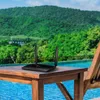 A black TP-Link Archer MR200 router with two antennas is placed on a wooden table next to a swimming pool, with lush green hills in the background. Podgląd zdjęcia produktu