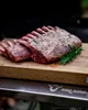 A rack of raw lamb seasoned with herbs and spices, placed on a wooden cutting board. Náhled obrázku produktu