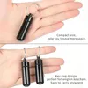 Hands holding small black pill containers with keychains. Produktbild-Vorschau
