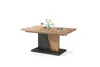 A modern dining table with a wooden top and a dark base, set against a white background. Decorative items like flowers and small bowls are placed on the table. Produktbild-Vorschau