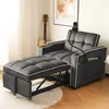 A dark gray convertible sofa bed is shown in a living room setting, with a guitar in the background and a phone holder attached to the sofa. Produktbild-Vorschau