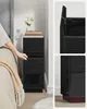 A hand is shown opening a drawer on a black nightstand next to a bed. Náhled obrázku produktu