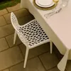 A white chair is placed next to a table set for a meal on a patio. Produktbild-Vorschau