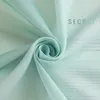 A close-up of a light green sheer fabric with text printed on it, arranged in a swirl. Produktbild-Vorschau