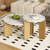 Two round terrazzo coffee tables with wooden legs are placed on a rug in a living room setting, with a sofa in the background. Voir les images du produit