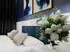 A bedroom scene with a bed, pillows, and artwork. Náhľad obrázku produktu