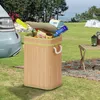 A bamboo trash can filled with items is placed on the grass next to a car, with tents and a table in the background, suggesting a camping or outdoor setting. Voir les images du produit